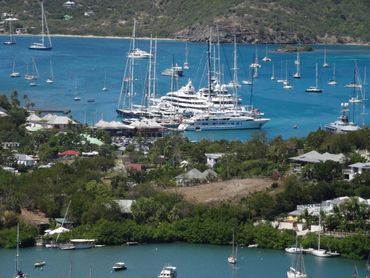 Eingang Nelson's Dockyard. Grosse, kleine Segelboote auf blauem Meer. Historische Gemäuer und grün