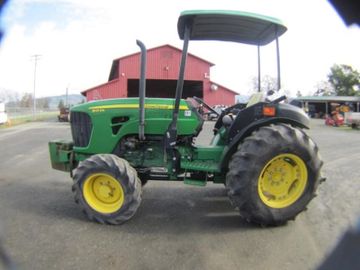 A green tractor parked near a red building