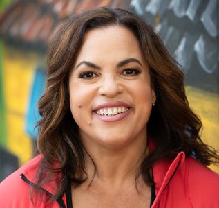 Smiling woman with wavy hair in a red jacket.