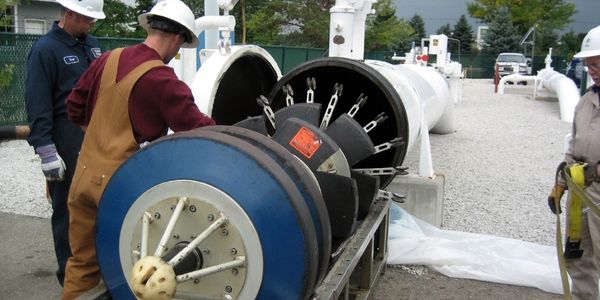 Pipeline operators loading pig tool into launcher vessel. Shown with threaded quick opening closure
