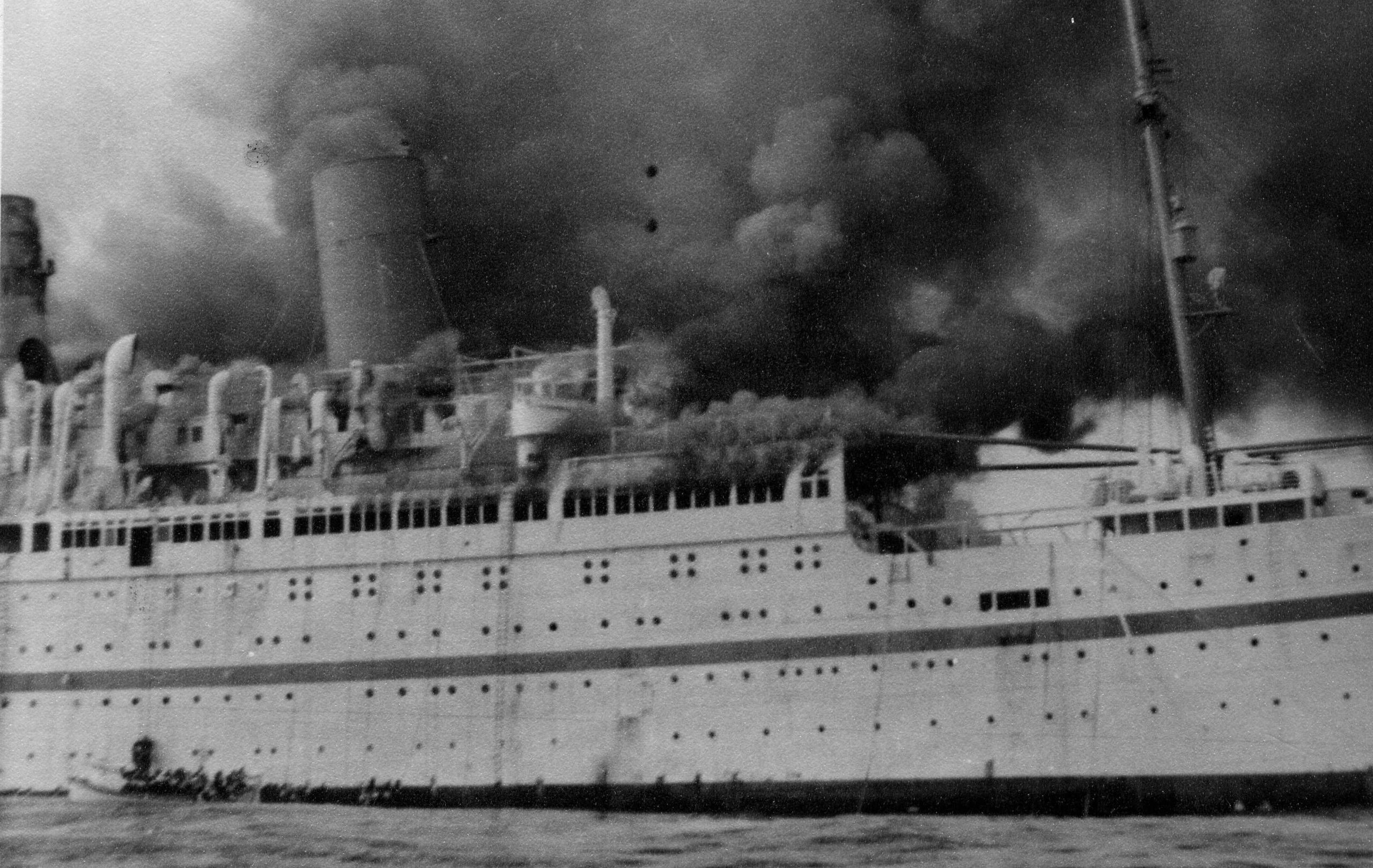 The Empire Windrush on fire, 1954, showing lifeboat being launched.
