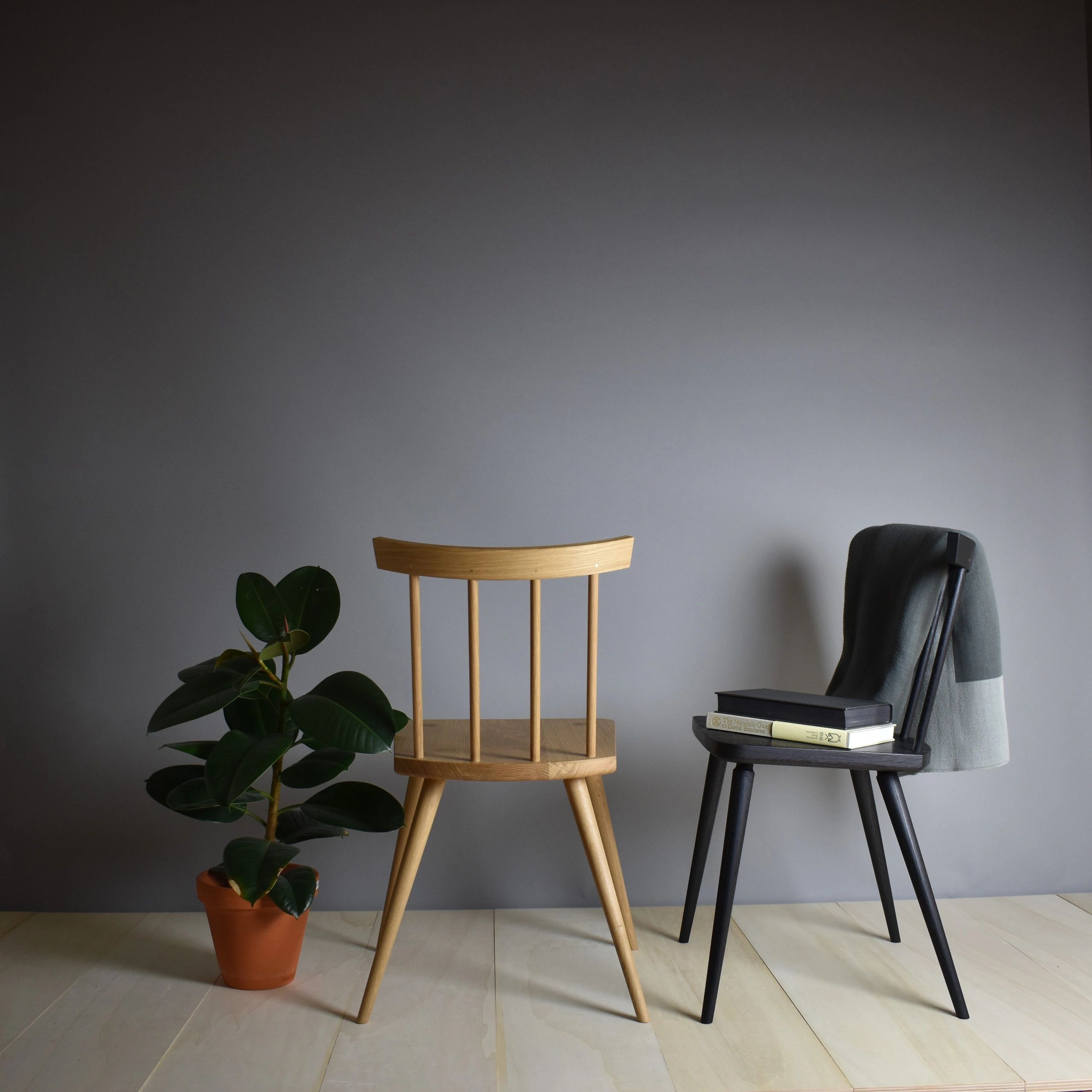 Honest dining chairs in Oak and ebonised Ash styled with books on design, a plant and a throw