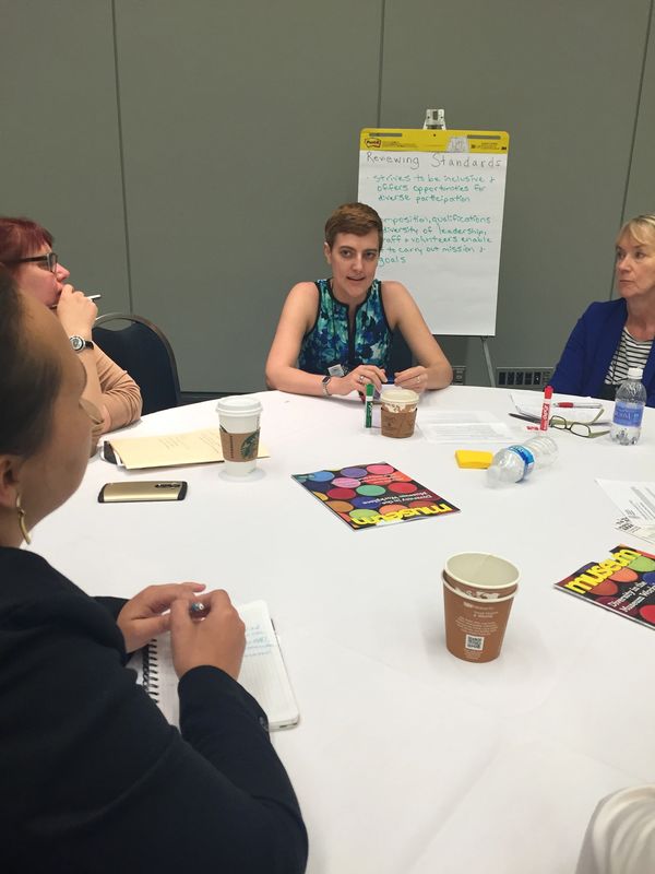 People talking at a round table with a whiteboard