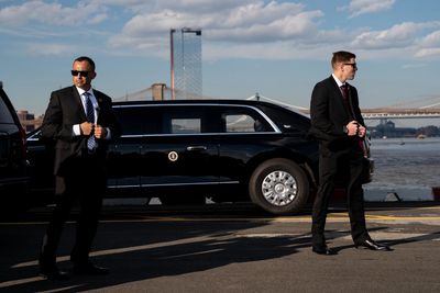 The US Secret Service are shown in front of the Presidential limousine.
