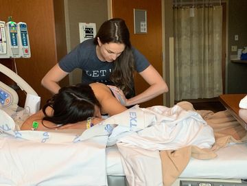 Birth doula doing hip squeezes on a mother in labor in the hospital setting.