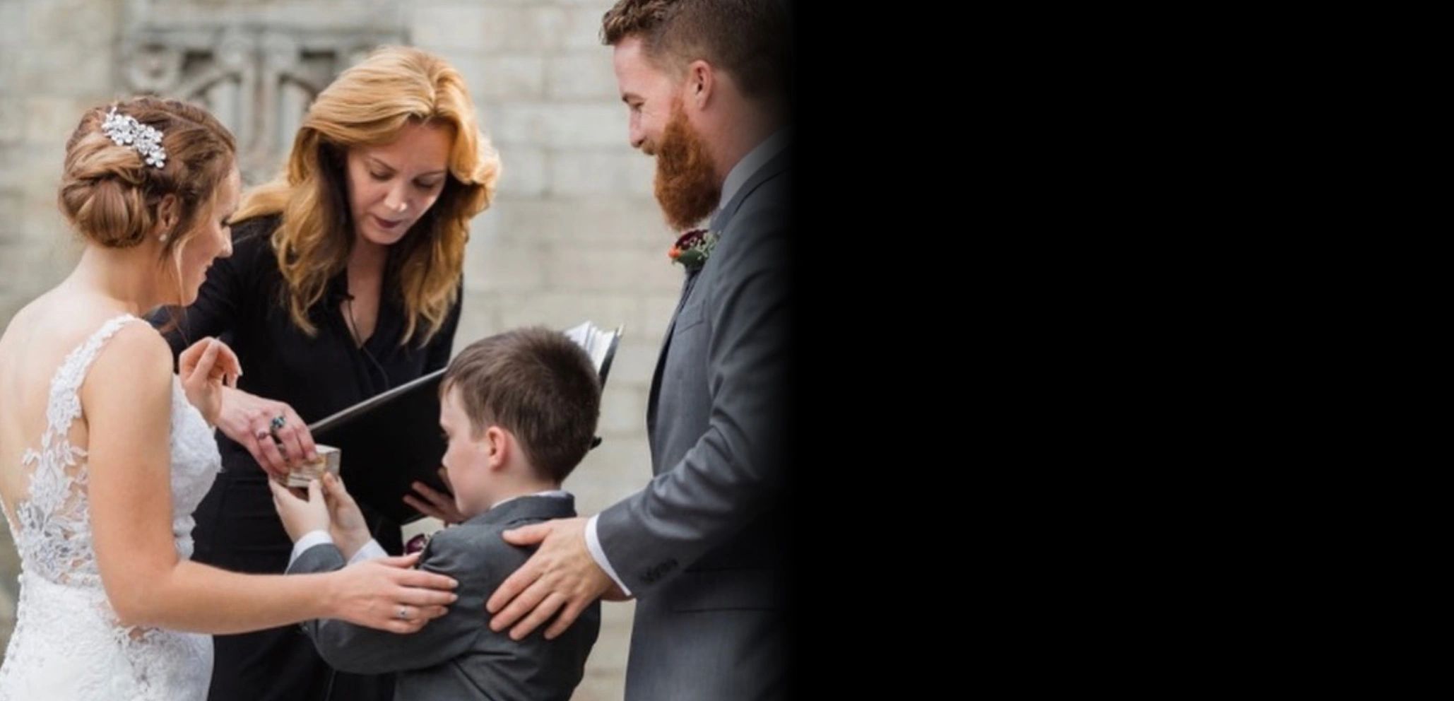 Jennie is taking the ring from the young ring bearer while a smiling bride and groom get married.