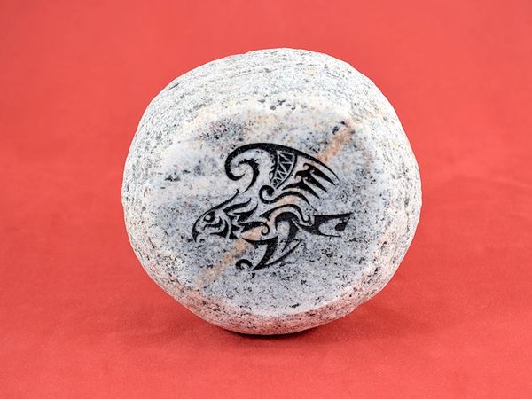 Engraved river rock with tribal artwork.