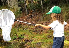 child with long hair holding net in pond