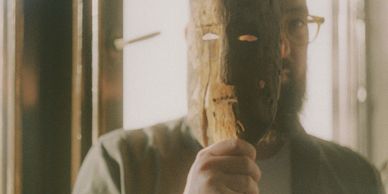 man wearing glasses and moving a mask away from his face.