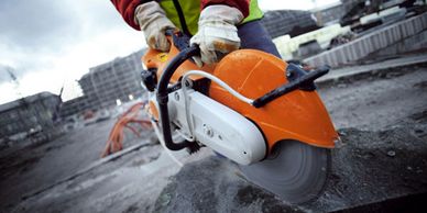 A picture of a person using a petrol cut saw cutting a concrete block.