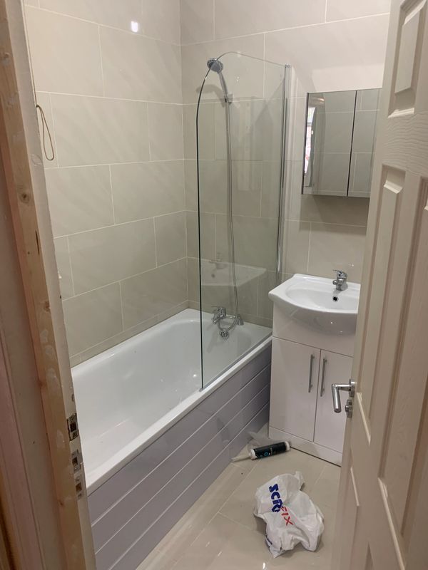 walls and floor tiled with a new bathroom fitted with screen, cabinet, toilet and basin vanity unit