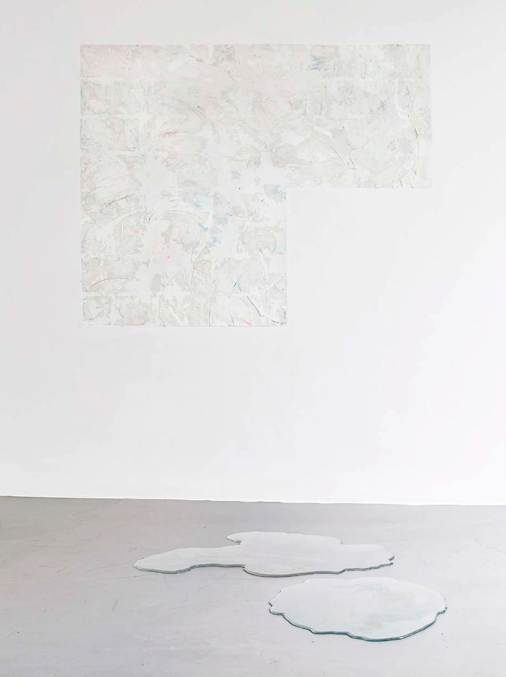 Abstract white textured artwork on wall with glass-like shapes on floor.