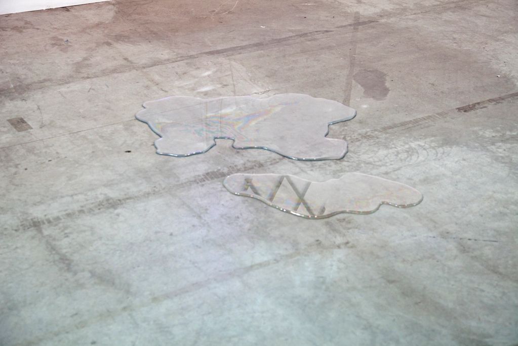 Two puddles of water on concrete floor.