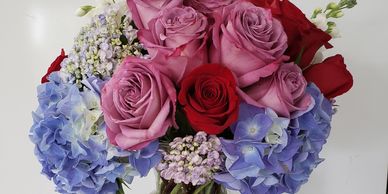 Purple and red roses, bluish lavender hydrangea and White stocks.Look us up under special moments flowers & gifts ltd