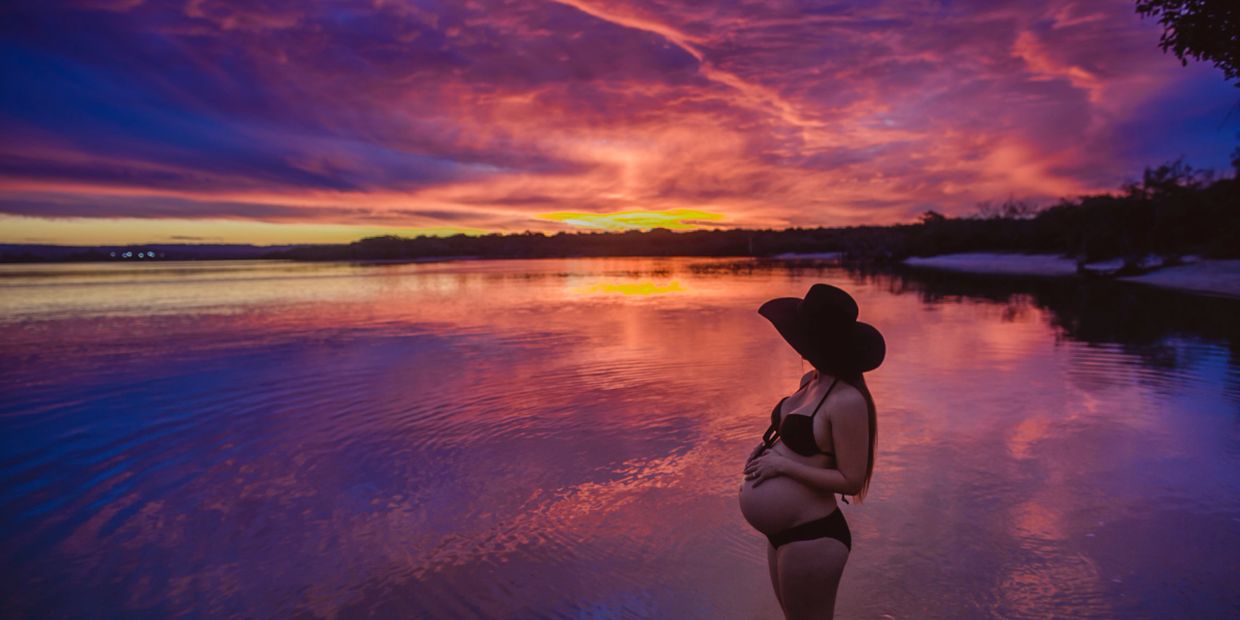 A pregnant woman in a calm lagoon watching a  sunset. Nashville, Mama Moon, prenatal wellness