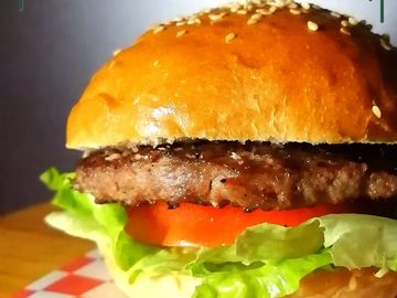 Close-up of a juicy burger with sesame seed bun and fresh lettuce.