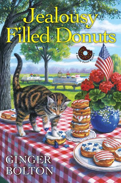 A cat named Deputy Donut squashing a blueberry filled donut on a table decorated for the Fourth of July on the cover of Jealousy Filled Donuts by Ginger Bolton