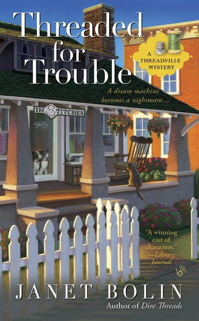 Two dogs looking through the glass door of the machine embroidery shop In Stitches in Threadville. A cat looks back at the dogs on the cover of Threaded for Trouble by Janet Bolin