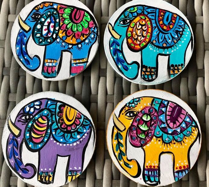 Four colorful, hand-painted elephant coasters with intricate designs.