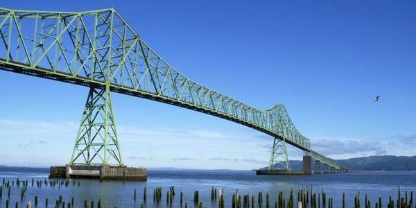 Astoria-Megler Bridge as seen from the shoreline of the Columbia River with old pier pylons