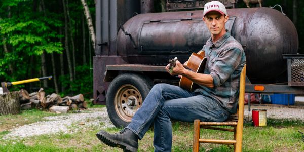 Cecil 3 picking the guitar in front of our Lang smoker