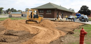 Denny Hall uses his bulldozer to move sand in preparation for Belding Veterans Park/Freedom Wall.