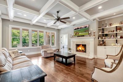 Living room with fireplace, coffered ceiling, crown molding, built-in cabinets, hardwood floors