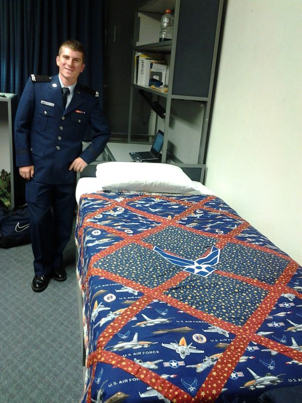 A Man Standing With a US Air Force Quilt on a Bed