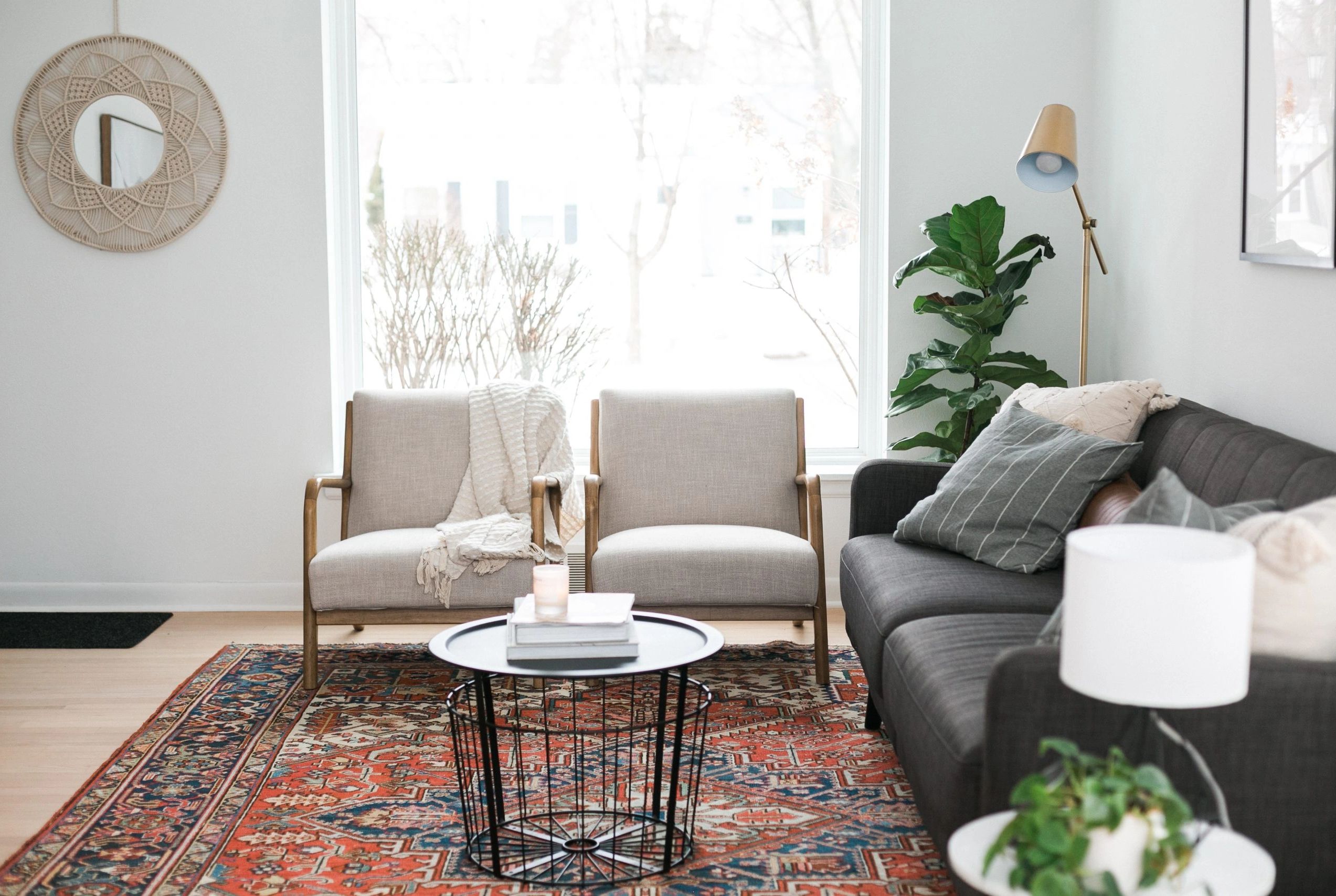 Cozy living room with two chairs, a gray sofa, and a patterned rug.