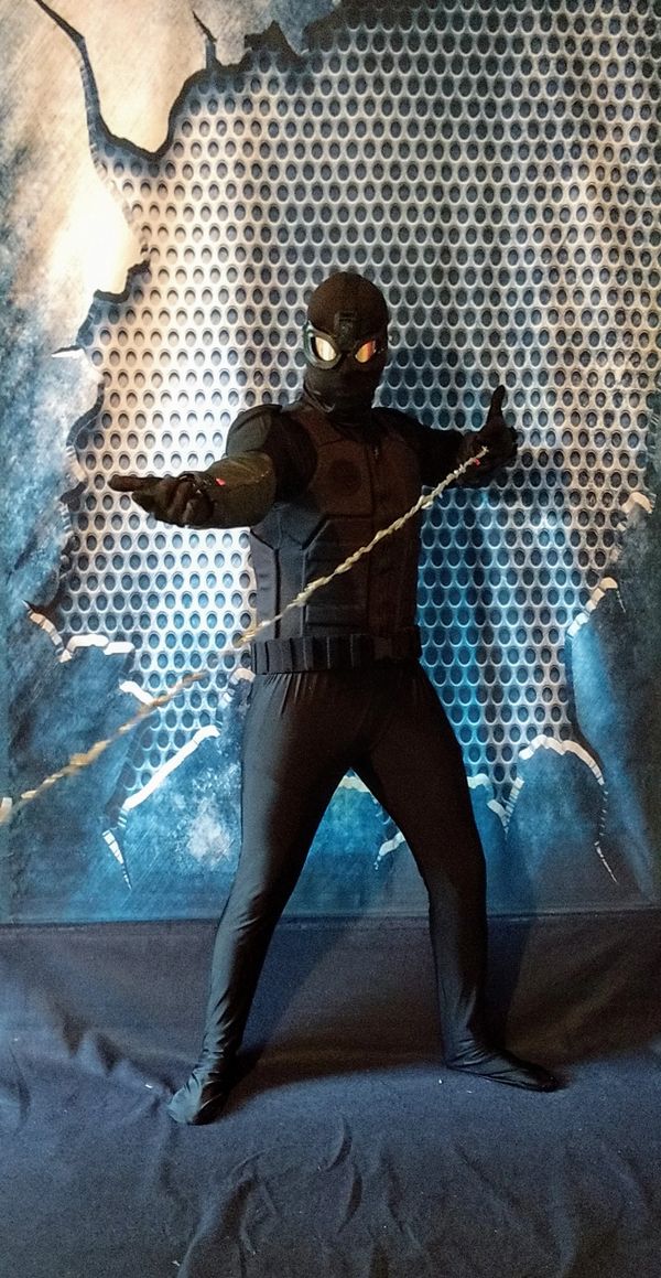 spider hero superhero party character with web in front of metal wall backdrop