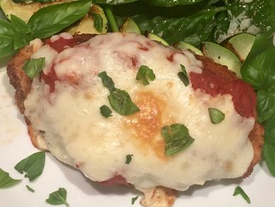 Chicken parmesan served with zucchini and a spinach salad.