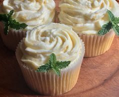 Peach cupcakes with peach mascarpone cheese frosting garnished with a sprig of mint.