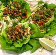 Asian lettuce wraps garnished with bean sprouts, lime wedges, and green onions.