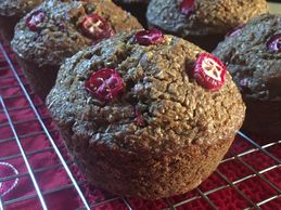 Cranberry Orange Bran muffins on a cooling rack on top of a tea towel.