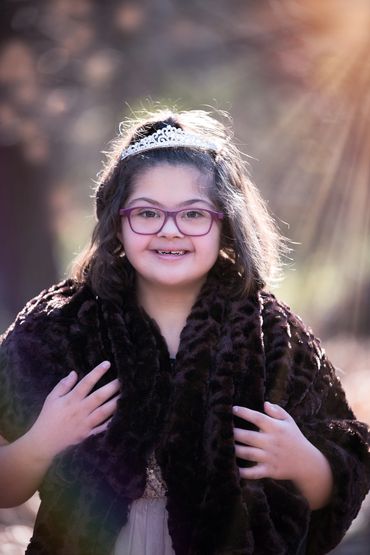 young girl in glasses smiling and wearing a crown