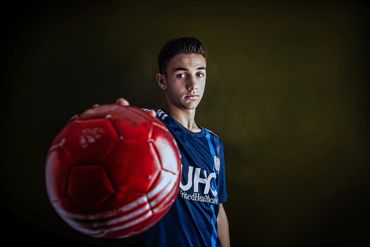 soccer teen holding a red soccer ball