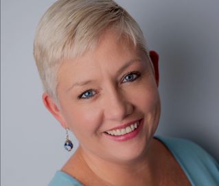 headshot of smiling woman with very short white hair