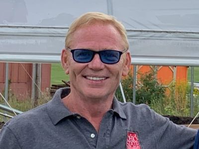 Light-skinned middle aged man wearing sunglasses and a grey polo shirt.