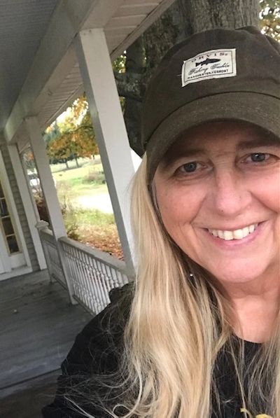 Selfie of Judith, a light-skinned woman, with long blonde hair wears a black baseball cap and shirt.