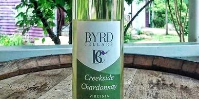 bottle of Byrd Cellars Creekside Chardonnay on wine barrel outside