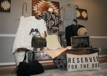 retail display of women's blouses, purse, decorative dog, throw pillow and wagon end table