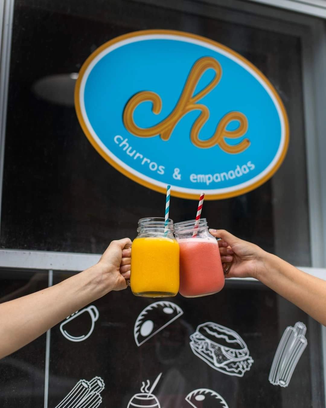 Deux main qui tiennent un jus naturel chaque dans un verre transparent devant une fenêtre.