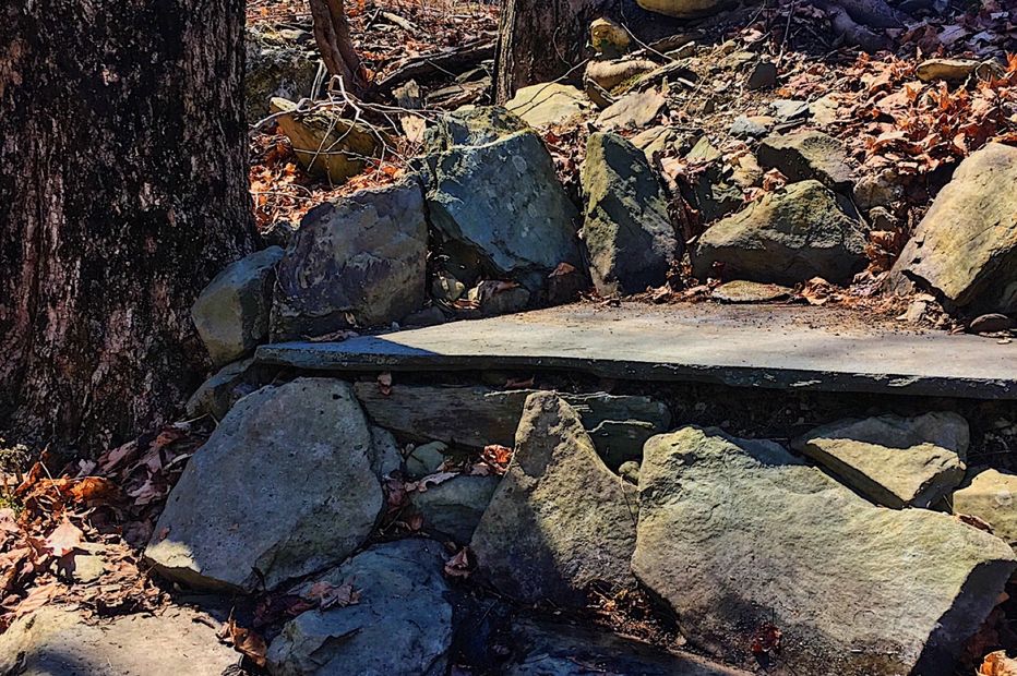 A rock loveseat is carved into the hillside to admire the surrounding scenery. It's comprised of a large flat irregular field stone as the base of the seat and carefully placed locally sourced boulders create the arms and back rest.