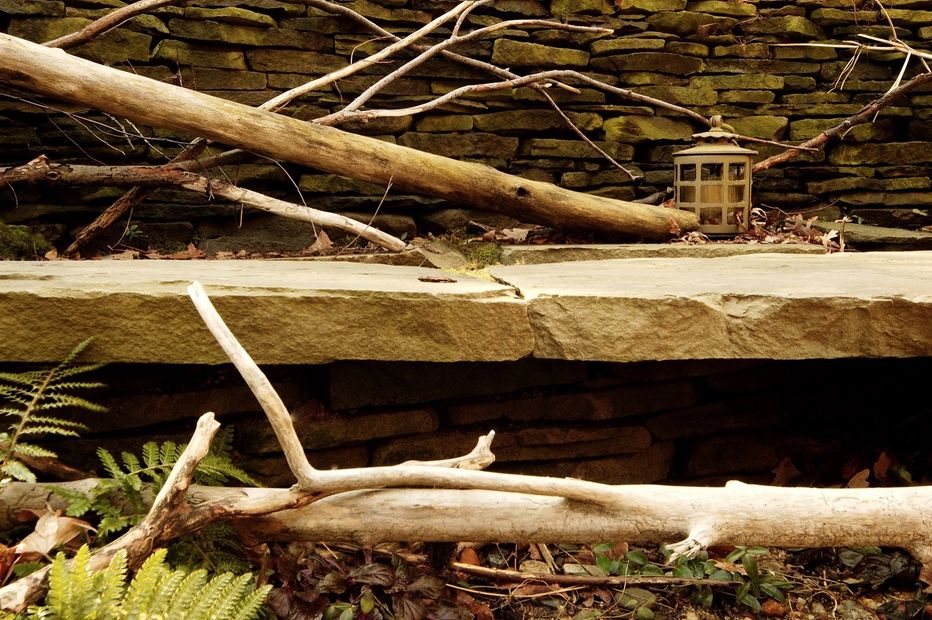 Cantilevered stone ledges with driftwood accents create a floating path with darkened spaces below and lite by periodic lanterns above for your unconscious mind to wonder, where does this lead to?