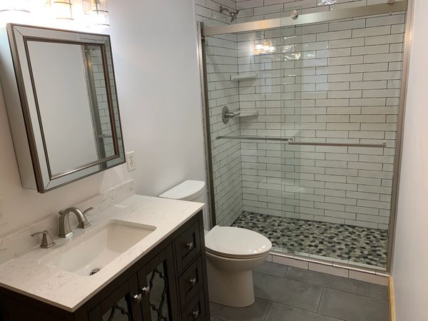 medicine cabinet, light fixtures, sink, vanity, toilet, shower tile, floor tile installation