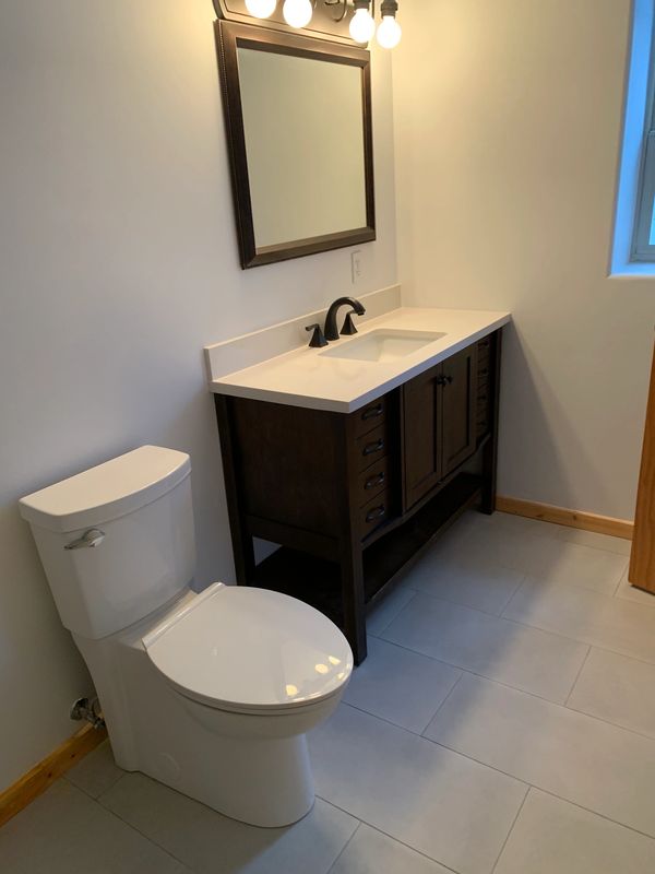 toilet, bathroom sink, vanity, light fixtures, floor tile installation