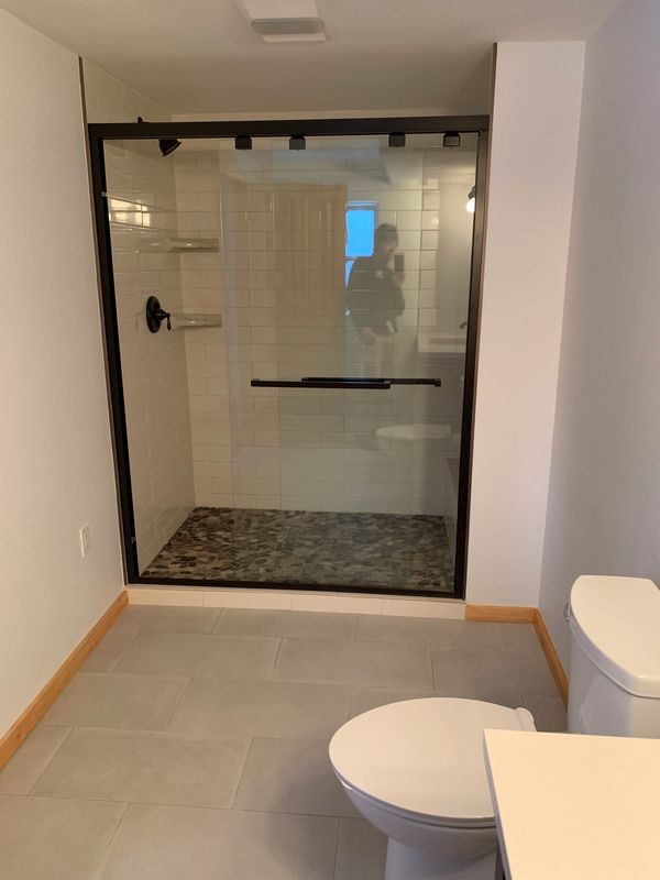 bathroom shower tile, floor tile, toilet, sink, glass door, baseboard installation, painted walls