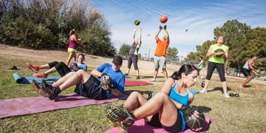 WorkoutStyles A group of men and women exercising in the park using medicine balls