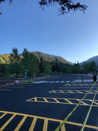 Empty parking lot near mountains under clear blue sky.