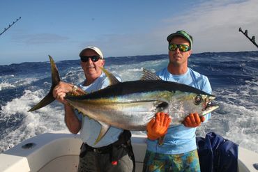 happy customer with tahiti sport fishing guided  charter, holding up a foot baller big eye tuna